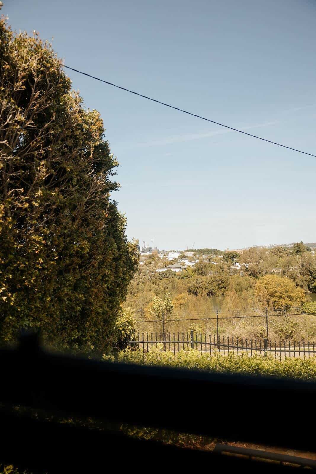 Vista desde una ventana de tren, con un árbol a la izquierda y una valla en primer plano.