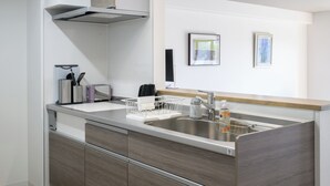 A modern kitchen with a stainless steel sink, wooden cabinets, and a built-in dishwasher. - LIT Hiroshima Ekimae (Hiroshima)