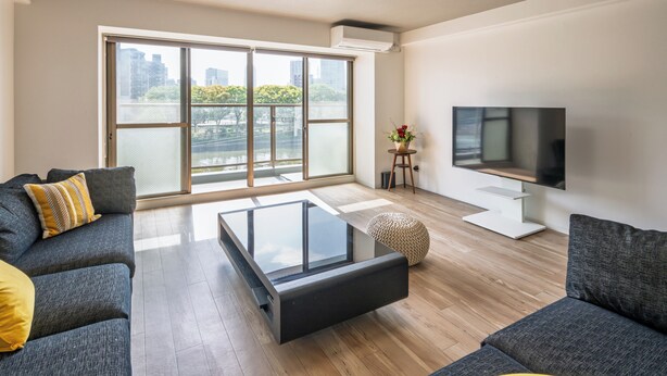 A modern living room with a large sliding glass door, a flat-screen TV, and a glass coffee table. - LIT Hiroshima Ekimae (Hiroshima)