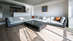A modern living room with a sectional sofa, a glass coffee table, and hardwood flooring. - LIT Hiroshima Ekimae (Hiroshima)