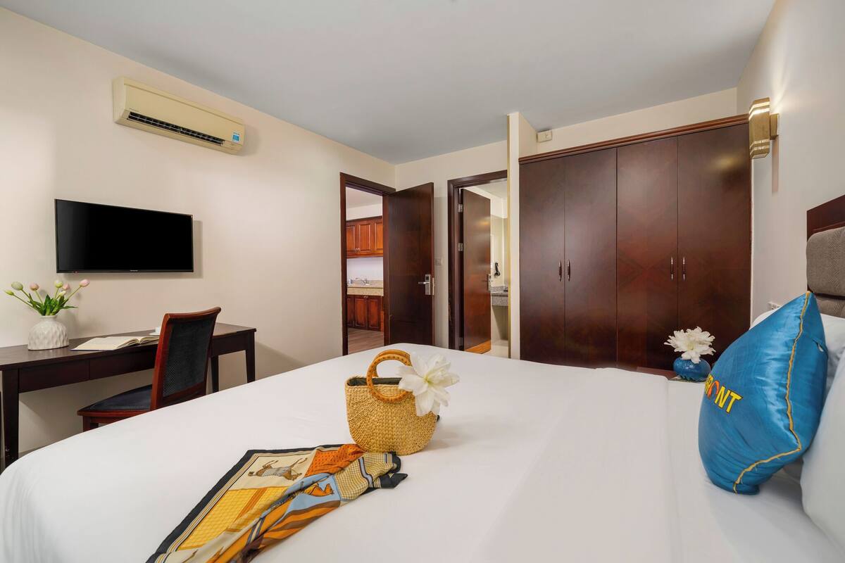 A hotel room with a bed, a desk, a television, and a wardrobe.