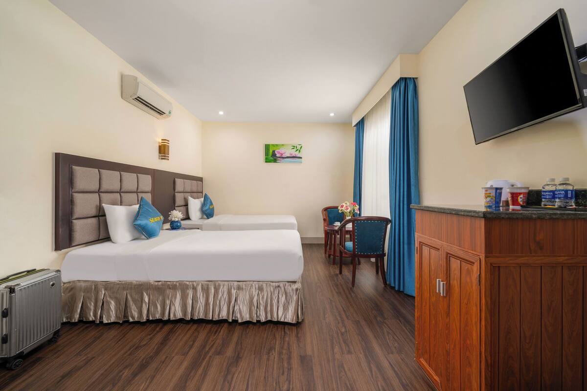 A hotel room with a bed, a TV, a desk, and a cabinet.