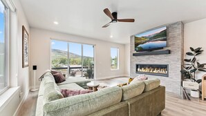 A spacious living room with a large sectional sofa, a fireplace, a flat-screen TV, and a ceiling fan. - 1301 Adams Ave - Silverthorne (Silverthorne)