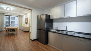 Una cocina moderna con electrodomésticos de acero inoxidable, una mesa de comedor de madera y vistas a la ciudad a través de grandes ventanales.