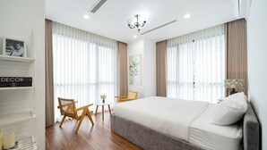 Una habitación de hotel moderna con una cama grande, suelo de madera, una araña y una estantería.