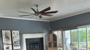 A spacious living room with a fireplace, a ceiling fan, and a large sliding glass door leading to an outdoor area. - SAUNA IS TEMPORARILY OUT OF SERVICE . (Norwich)