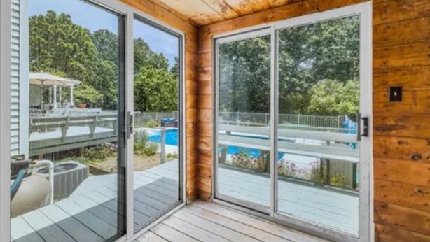 A wooden cabin with large sliding glass doors leading to a deck with a pool. - SAUNA IS TEMPORARILY OUT OF SERVICE . (Norwich)