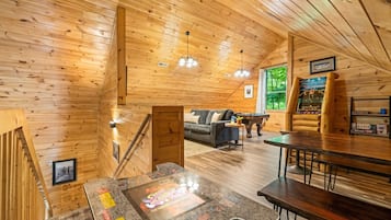 L’intérieur d’un chalet en bois chaleureux et accueillant, avec un coin repas, un canapé et une table de billard.