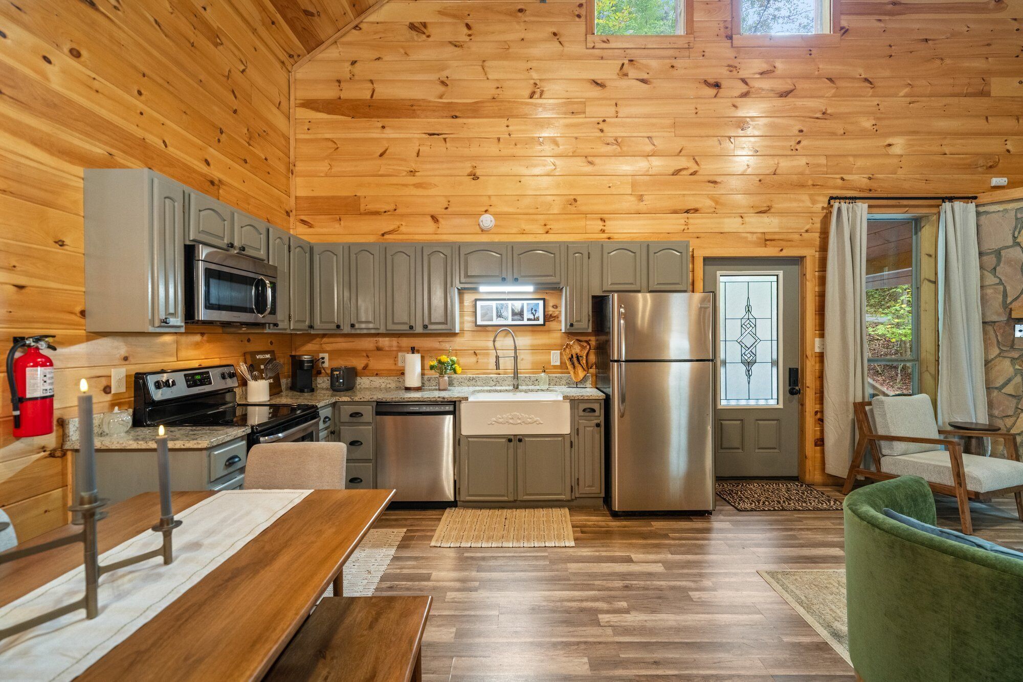 A cozy cabin-style kitchen with wooden walls, a stainless steel refrigerator, and a built-in microwave.