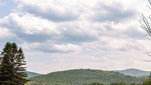 A river flowing through a green landscape with hills in the background. - White Mountain Cottage, Birchcliff (Shelburne)