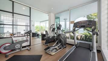 A home gym with exercise equipment, large windows, and a view of greenery.