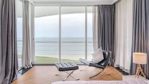 Ein modernes Hotelzimmer mit einer großen Schiebetür zu einem Balkon mit Meerblick.
