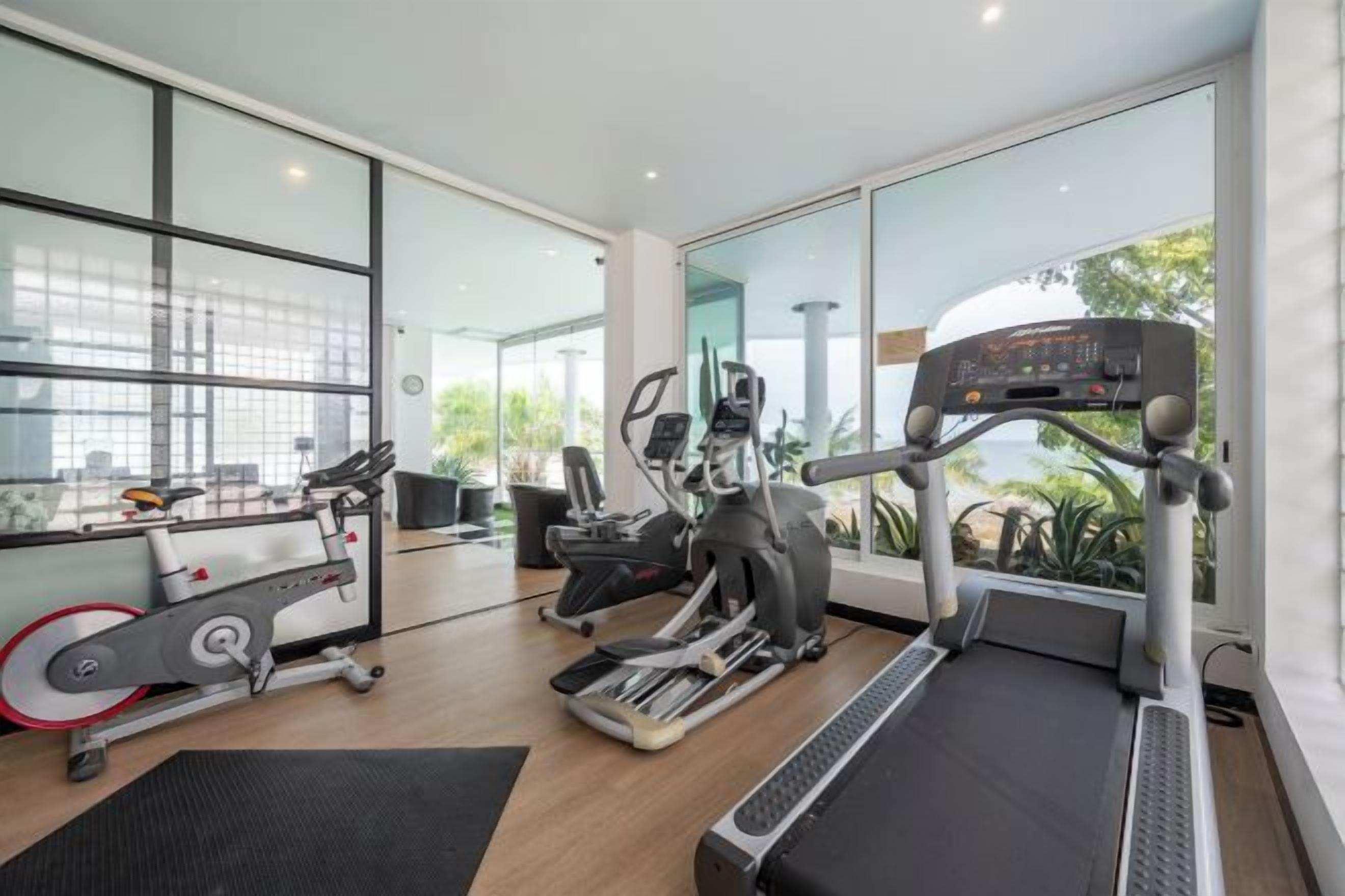 A modern gym with cardio machines, a treadmill, and a rowing machine.