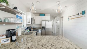 A modern kitchen with granite countertops, stainless steel appliances, and pendant lighting. - Seaside Escape | Pool • Ocean Views • Family Ready (Navarre)