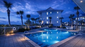 A swimming pool with a lifeguard stand, palm trees, and a building with balconies. - Seaside Escape | Pool • Ocean Views • Family Ready (Navarre)