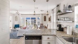 A modern kitchen with granite countertops, stainless steel appliances, pendant lighting, and a view to the outside. - Seaside Escape | Pool • Ocean Views • Family Ready (Navarre)