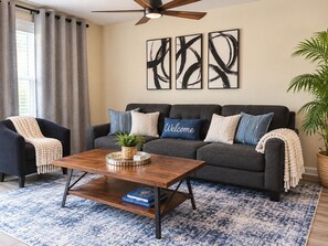 Un salon avec un canapé gris foncé, une table basse en bois et un tapis à motifs bleus.