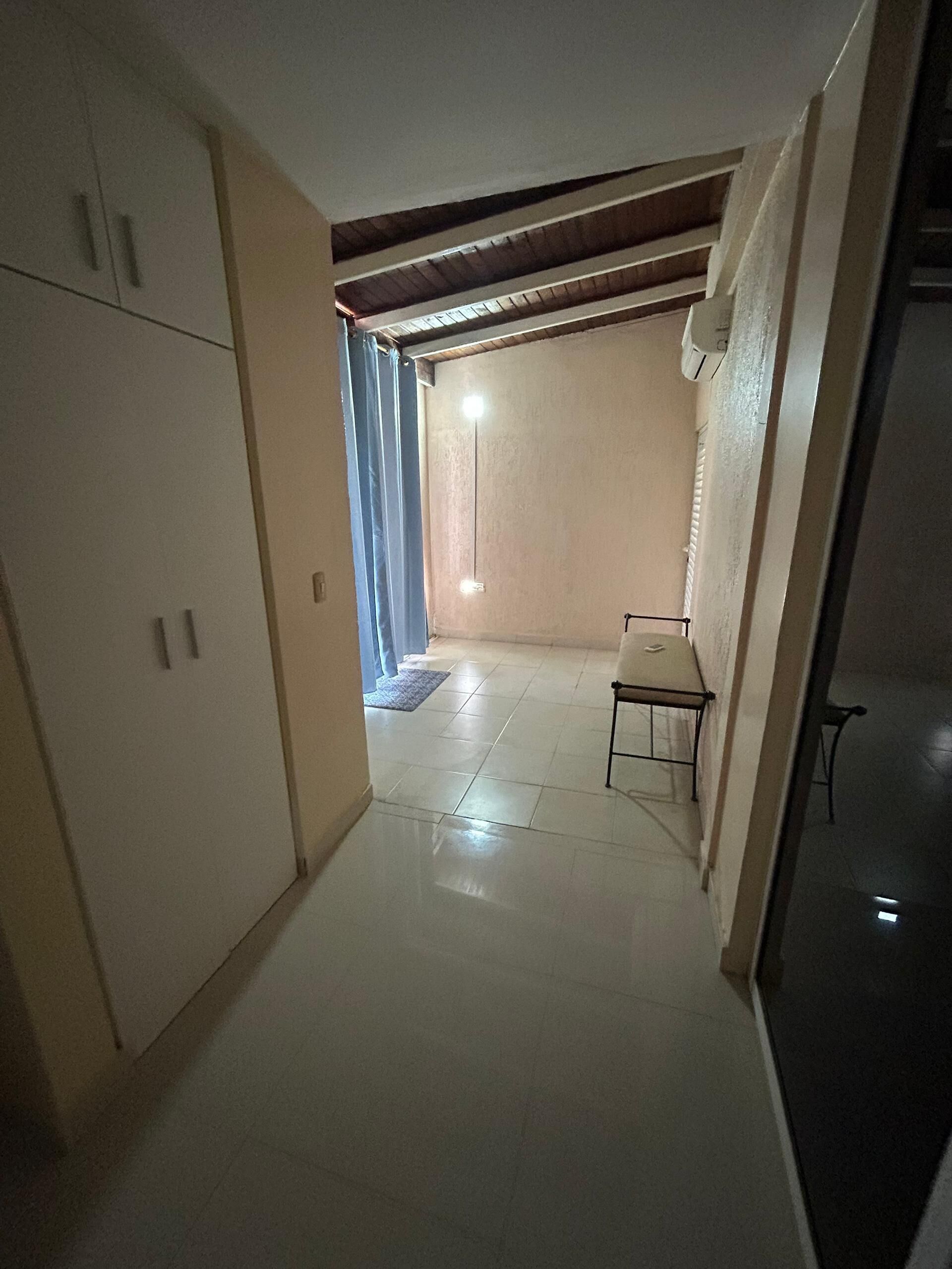 A narrow hallway with a tiled floor, a bed with a metal frame, and a wardrobe.