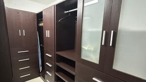 Um closet amplo com armários de madeira escura, diversas prateleiras e porta com espelho.