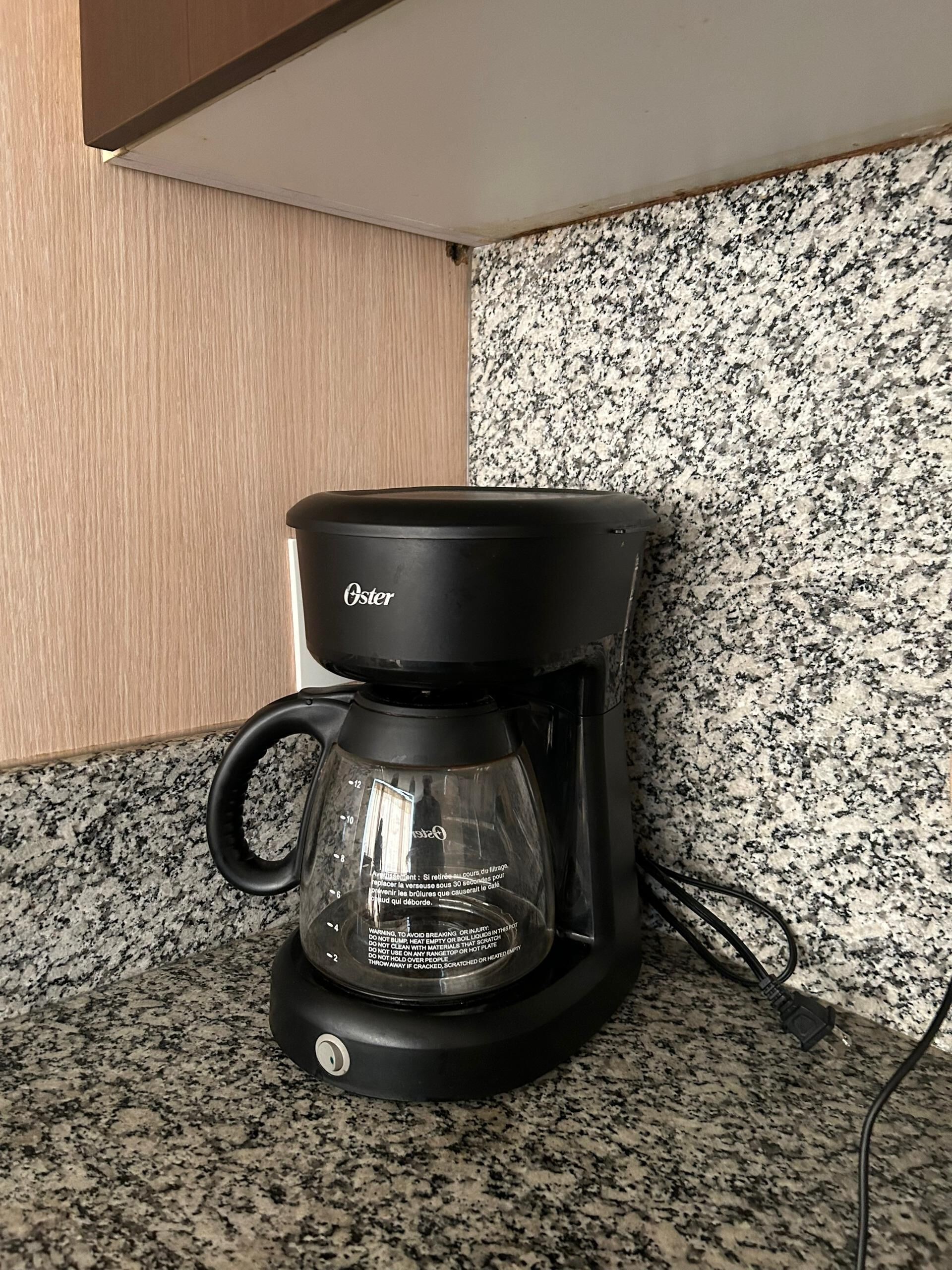A black coffee maker with a glass carafe on a granite countertop.
