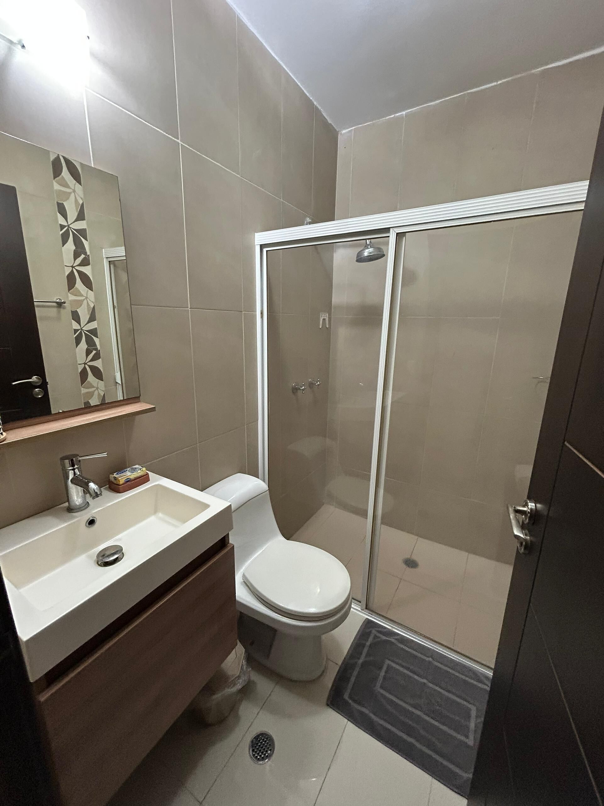 Ein Badezimmer mit Dusche, Toilette, Waschbecken und Spiegel.
