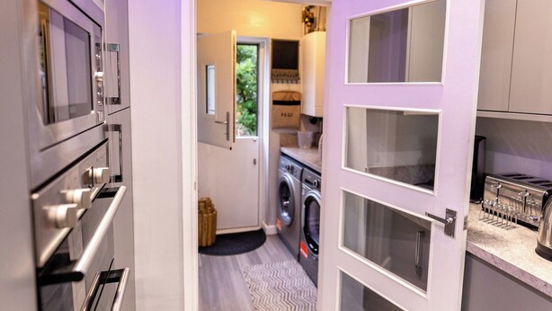 A compact kitchen with a washing machine, a built-in oven, and a toaster. - 3Bedroom-Sleeps5-WiFi-SingleCarParking (Manchester)
