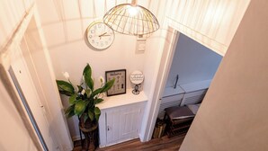 A staircase with a wooden floor, a white door, a potted plant, a clock, and a welcome sign. - 3Bedroom-Sleeps5-WiFi-SingleCarParking (Manchester)