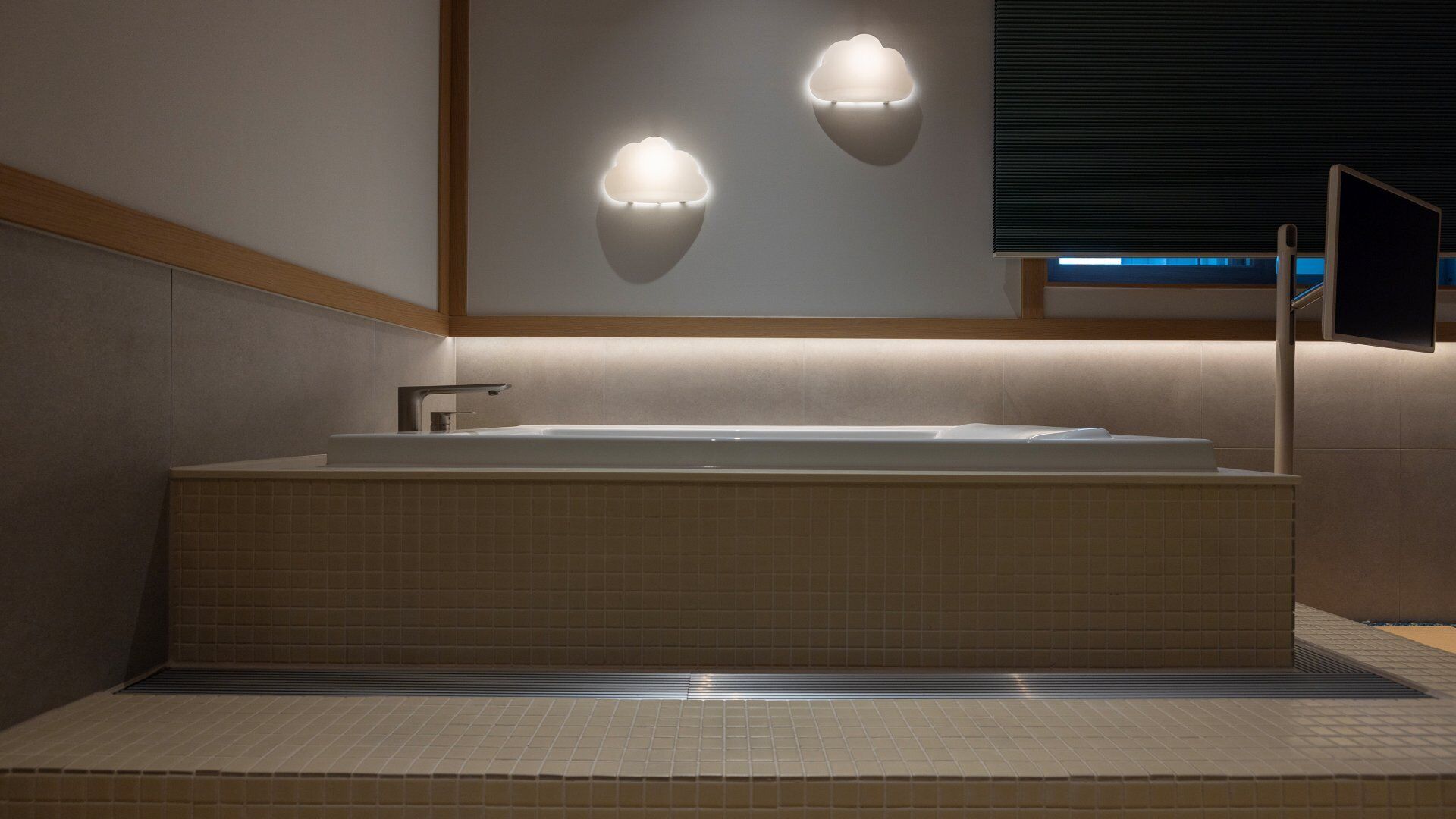 A modern bathroom with a freestanding bathtub, two wall-mounted lights, and a large mirror.
