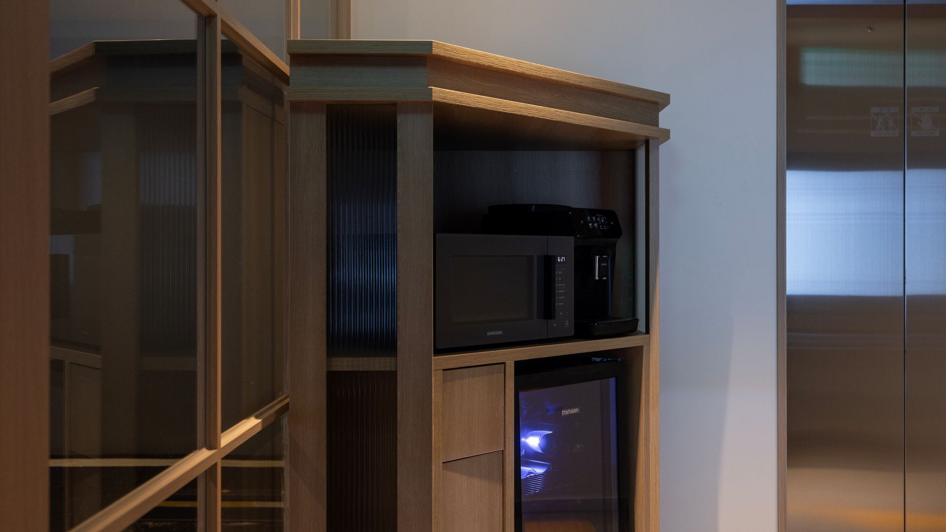 A modern kitchen with a built-in microwave and coffee maker on a wooden shelf.