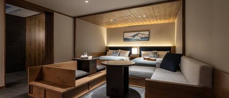 A modern hotel room with a bed, a sofa, a small table, and a wooden bench.