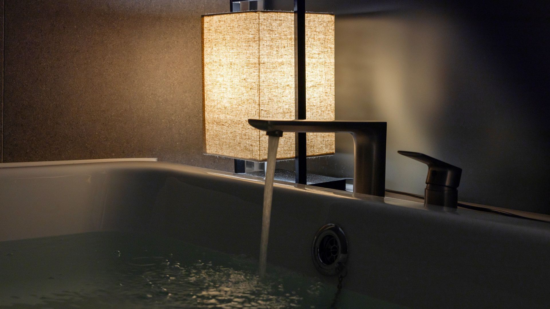 A modern bathroom with a bathtub, a towel rack, and a wall-mounted towel dispenser.