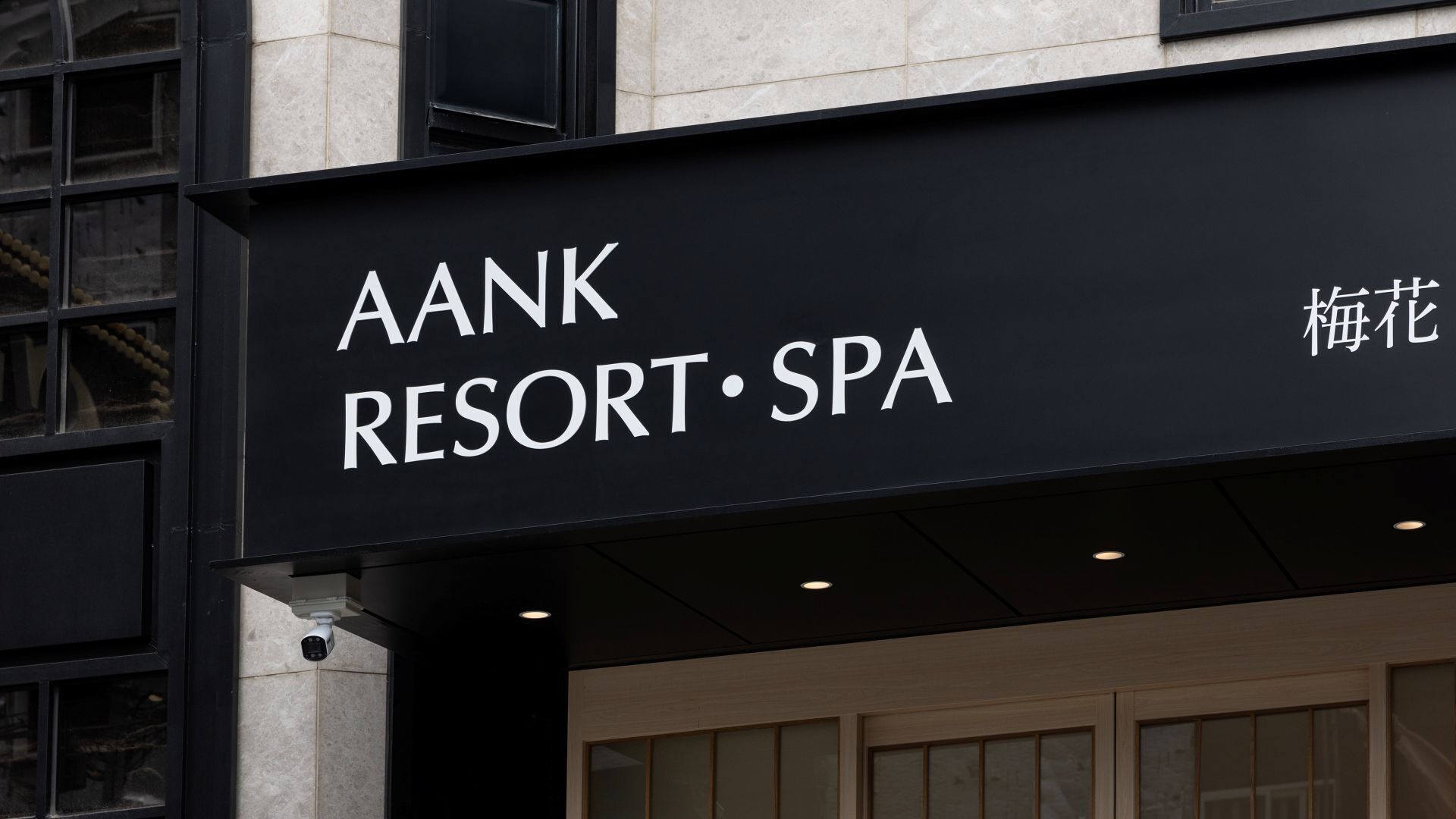 Schild für AANK Resort & Spa mit modernem Design und einer an der Wand montierten Überwachungskamera.