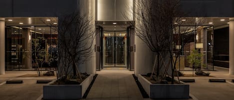 A modern building with a glass entrance, a sign reading 'ANOOK Signature', and a pathway leading to the entrance.