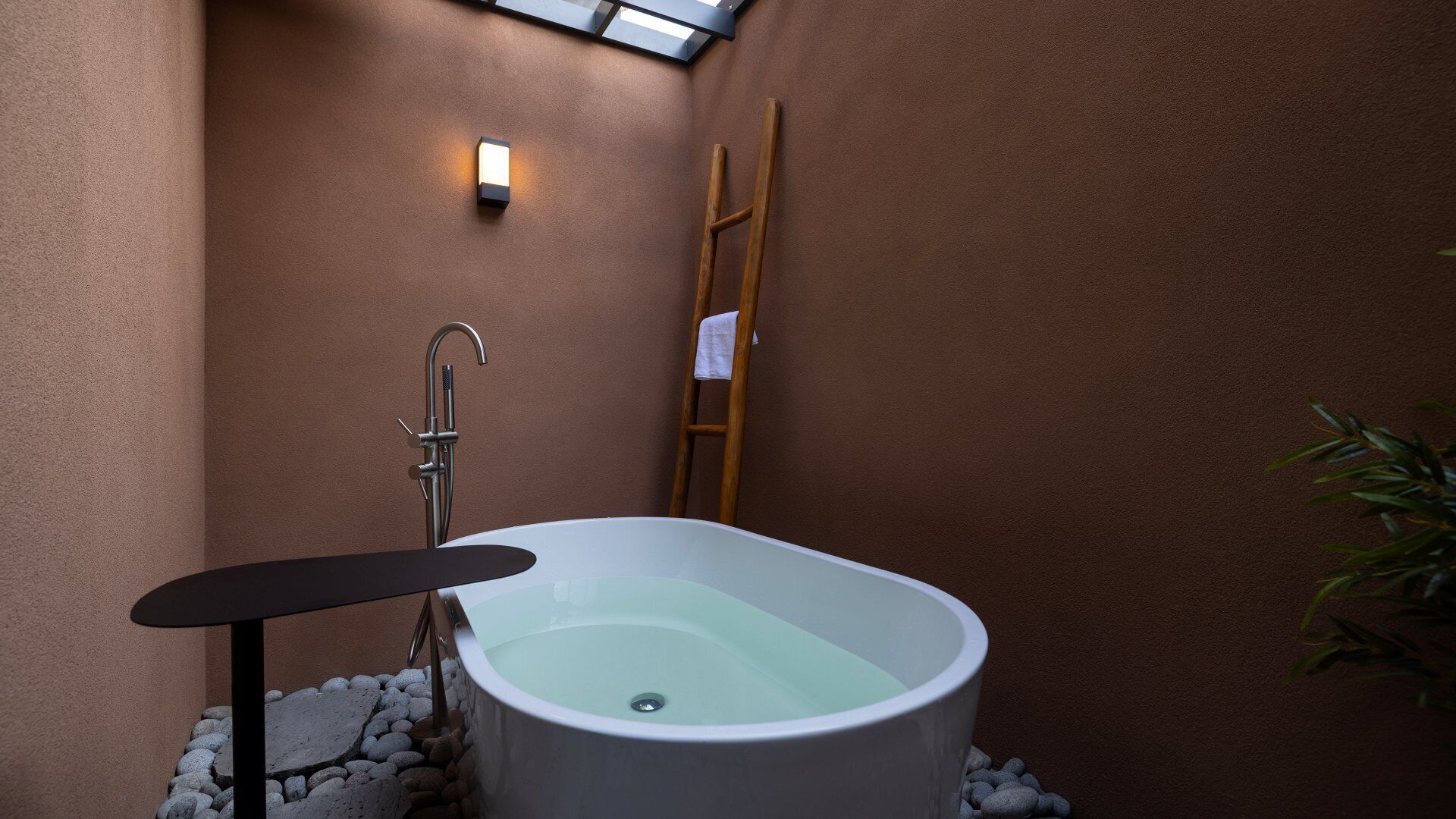 A spa bathroom with a freestanding bathtub, a wooden ladder, and a small table.