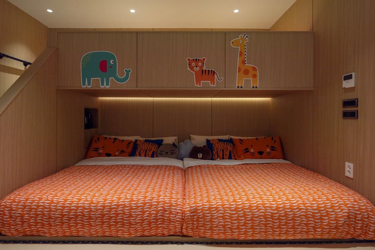 A bedroom with a double bed, two pillows, and a headboard with animal cutouts.