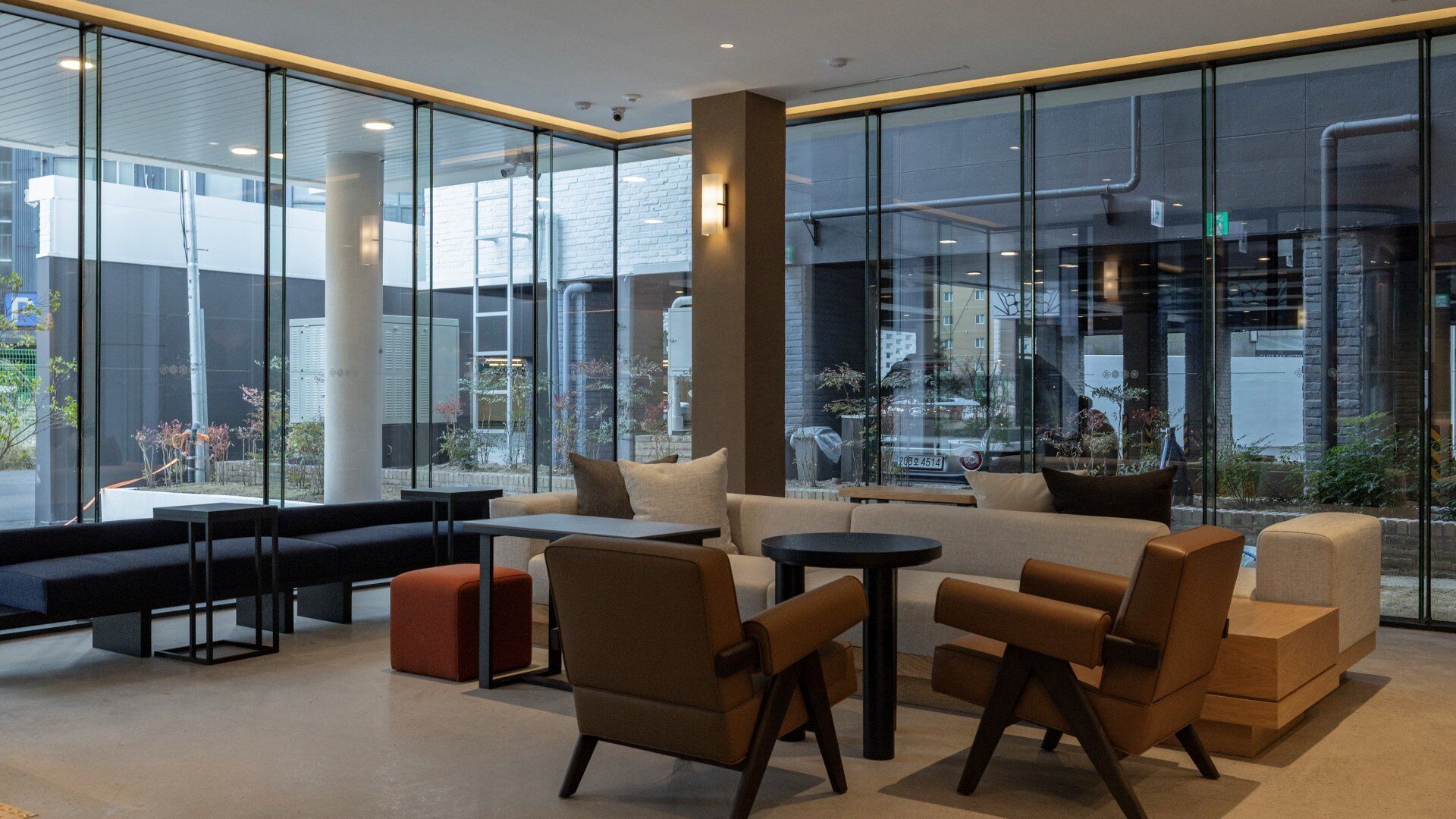 A modern lobby with seating arrangements, large windows, and visible outdoor elements.