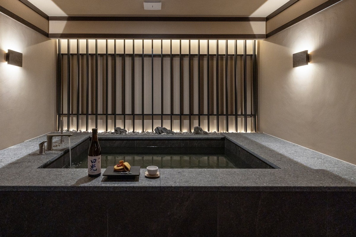 A modern bathroom with a stone sink, a bottle of shampoo, and a cup.
