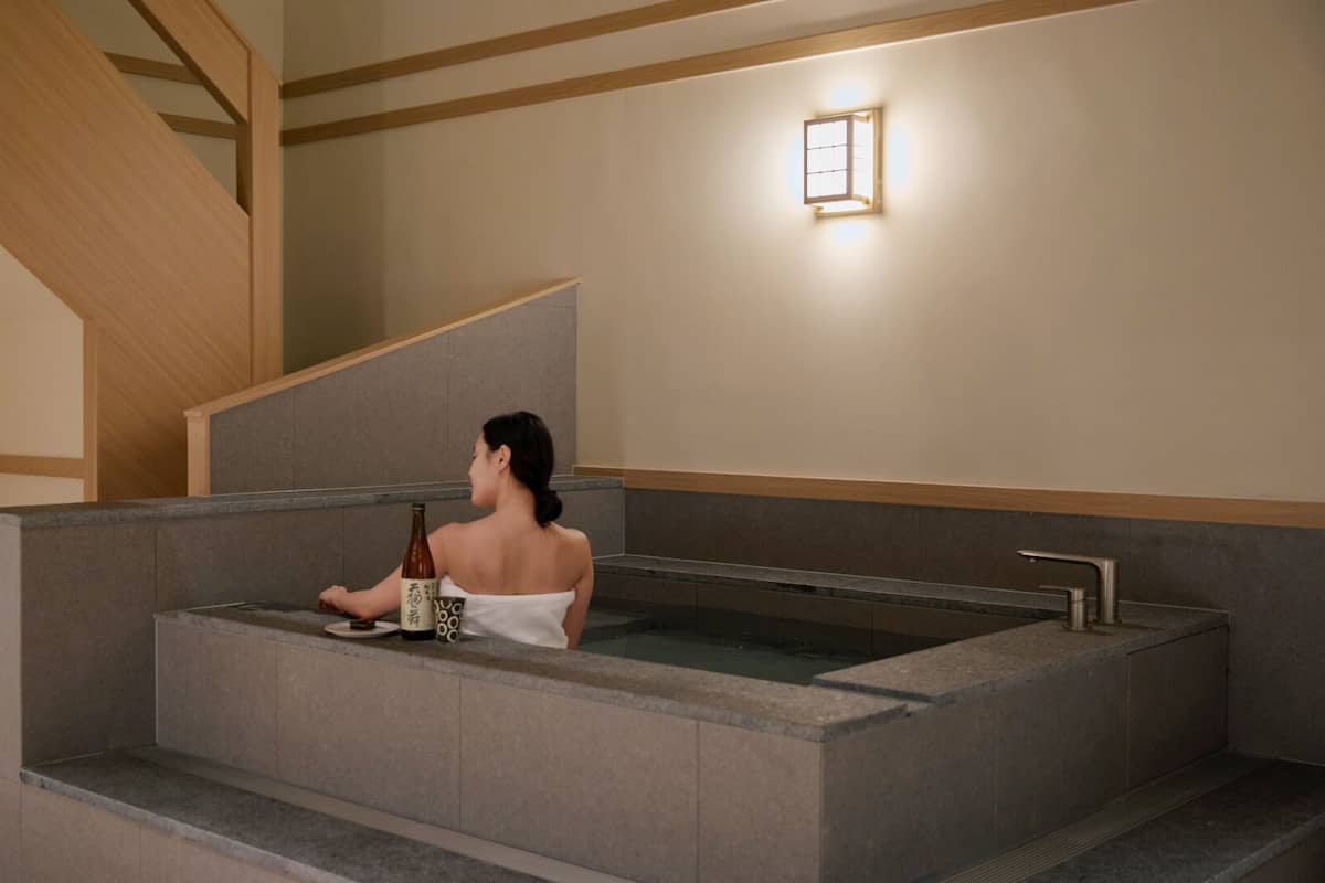 A spa area with a hot tub, a wooden staircase, and a wall-mounted light fixture.