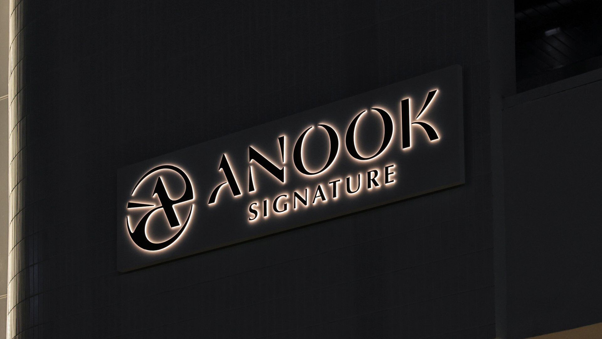 Une enseigne avec le texte « ANOOK SIGNATURE » sur un fond sombre.