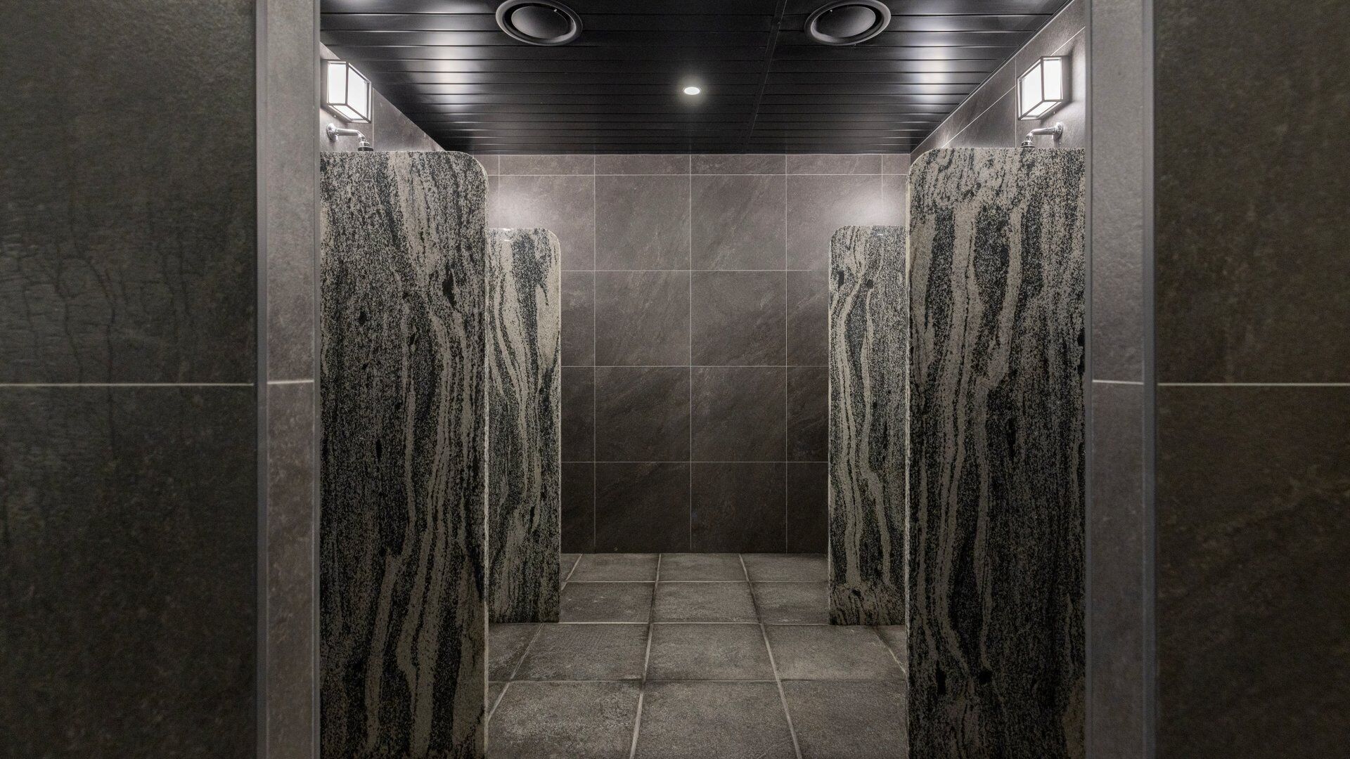 A modern bathroom with a dark ceiling, tiled walls, and a central shower area.