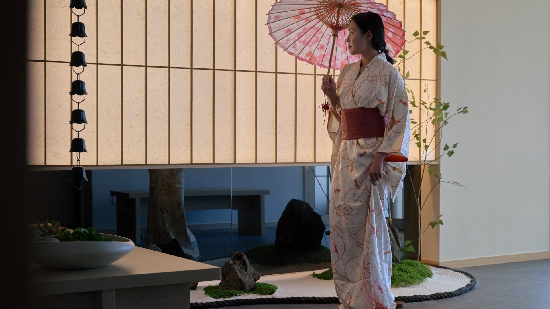 A traditional Japanese interior with tatami flooring, a low table, and a decorative plant arrangement.