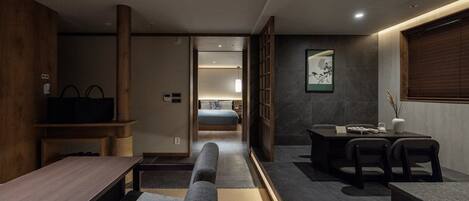 Una habitación de hotel moderna con diseño minimalista, que incluye un sofá, una mesa de comedor y una cama con vistas a la ciudad.