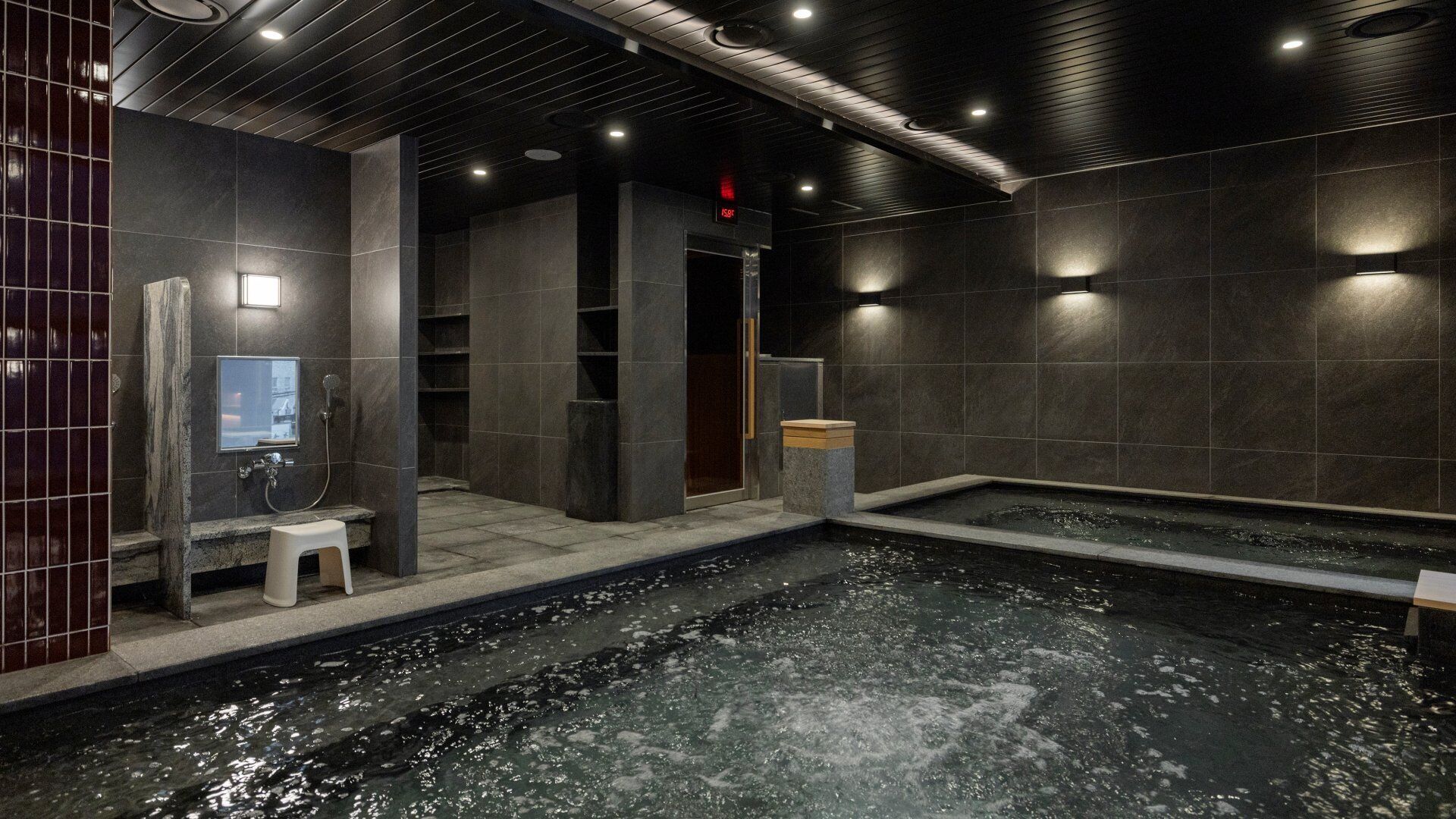Un spa moderne doté d’un jacuzzi, de murs en pierre et d’un banc en bois.
