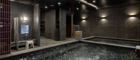 Un spa moderne doté d’un jacuzzi, de murs en pierre et d’un banc en bois.