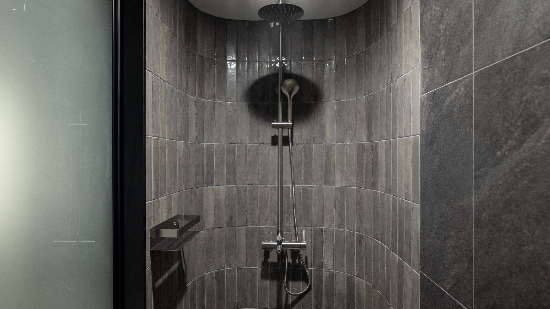 A modern shower with a handheld showerhead and a wall-mounted faucet.