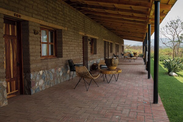 A covered patio with brick flooring, outdoor seating, and a view of the surrounding landscape. - Casa Xaguar (Miahuatlan de Porfirio Diaz)