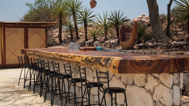 A bar area with stone walls and black chairs. - Casa Xaguar (Miahuatlan de Porfirio Diaz)