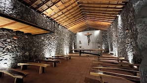 A church interior with stone walls, wooden pews, a wooden ceiling, and a crucifix. - Casa Xaguar (Miahuatlan de Porfirio Diaz)