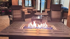 Een vuurkorftafel met stoelen, een ronde tafel en een patio met zitplaatsen.