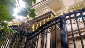 A gated entrance with ornate black metalwork and gold accents, leading to a building with classical architecture and multiple windows. - Van Loi Home (Ho Chi Minh City)